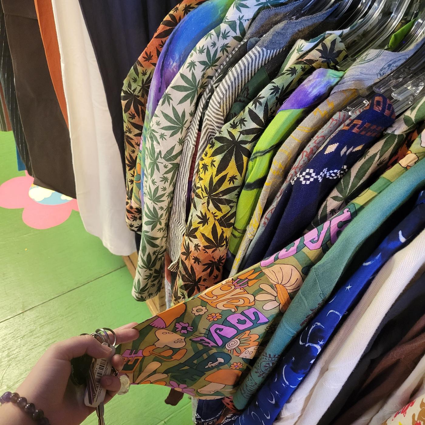A rack of printed cotton shirts in leaf, mushroom and tie dye patterns.