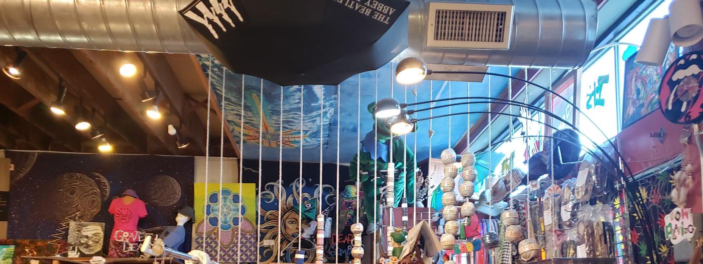 Hanging hacky sacks and beaded goods below a ceiling hung with an umbrella and painted panels.